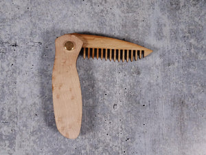 Folding tactical beard comb featuring a birdseye maple handle and a bamboo ply blade